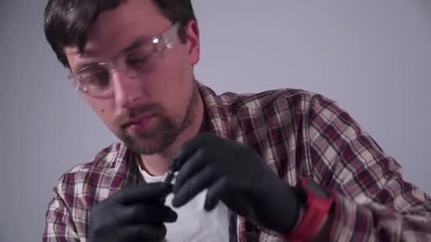 Ein junger Mann versucht, seine eigenen Küchengeräte zu Hause zu reparieren, eine Kaffeemaschine. Kaukasischer Mann repariert Kaffeemaschine mit Schraubenzieher in kariertem Hemd und Schutzbrille und Handschuhen — Stockvideo