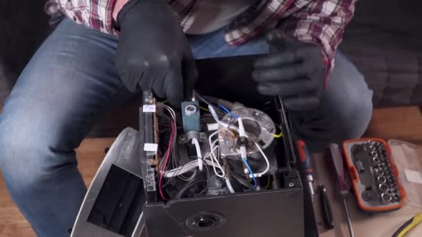 Ein junger Mann versucht, seine eigenen Küchengeräte zu Hause zu reparieren, eine Kaffeemaschine. Kaukasischer Mann repariert Kaffeemaschine mit Schraubenzieher in kariertem Hemd und Schutzbrille und Handschuhen — Stockvideo