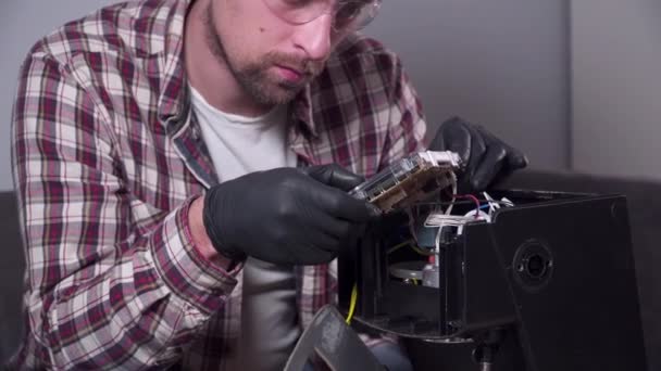 Trying to fix coffee machine. Service and repair of coffee maker. Adult handyman repairing coffee machine by screwdriver at home. Male mend percolator in goggles and black rubber gloves — Stock Video