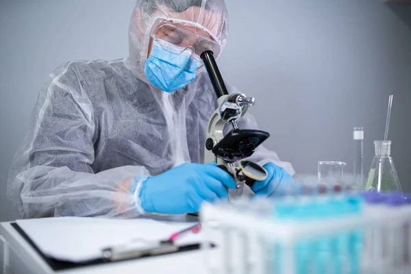Profesional Medis Dalam Pakaian Pelindung Putih Melihat Melalui Mikroskop Laboratorium — Stok Foto