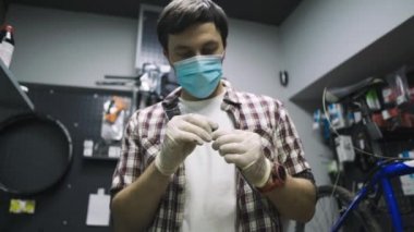 Bisiklet tamircisi Coronavirus salgını sırasında karantina standartlarına uygun olarak bisiklet tamir eder ve bakımını yapar. Tıbbi maske ve eldiven takar. Covid 19 'u kilitlerken bireysel taşıma