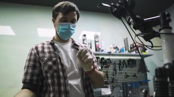 Bicycle mechanic repairs and maintains customer bike in accordance with quarantine standards during coronavirus pandemic, wear medical mask and gloves. Individual transport during lockdown covid 19 — Stock Video