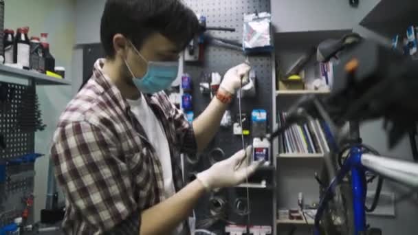 Service à thème entretien et réparation de vélo dans le magasin de vélos pendant l'épidémie de coronavirus. Mécanicien réparations vélo de montagne portant un masque de protection, nouvelles règles covid 19. Sujet ouvrier profession — Video