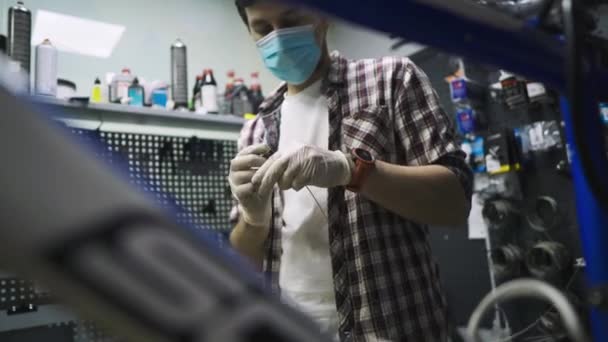 Ingeniero de servicio realiza diagnósticos y reparaciones en bicicleta en taller profesional, usando máscara protectora y guantes de seguridad del cliente covid 19. Tema de servicio durante la pandemia de coronavirus — Vídeo de stock