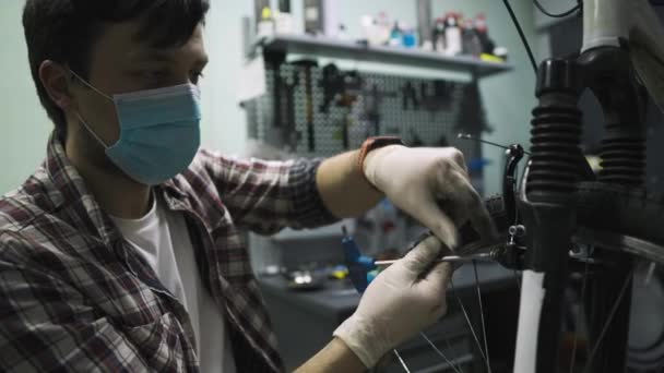 Bicycle mechanic repairs and maintains customer bike in accordance with quarantine standards during coronavirus pandemic, wear medical mask and gloves. Individual transport during lockdown covid 19 — Stock Video