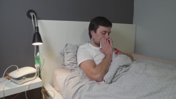 Erkek, kovid 19 koronavirüs salgını sırasında yatakta yatarken üst ve alt solunum yolları hastalıklarını, astım ve alerjileri tedavi ederek solunum maskesiyle nefes alır. — Stok video