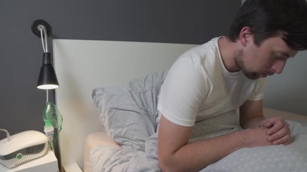 Hombre con coronavirus, gripe usando mascarilla inhaladora de medicamentos nebulizadores en la cama. Medicina respiratoria. Tratamiento respiratorio del asma. Bronquitis, equipo de salud asmático. Tratamientos caseros alternativos — Vídeos de Stock