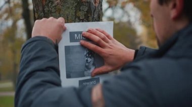 Kayıp evcil hayvan sahibi parkta köpeğini kaybettiğini gösteren bir afiş asıyor. Kayıp köpeğin posterlerini yapıştıran adam. Kayıp köpek ilanı parktaki bir ağaçta asılı duruyor. Kayıp köpek.