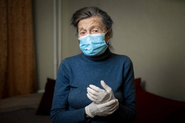 Old Caucasian woman dressed in personal protective equipment, mask and gloves, encourages to stay at home during an epidemic for safety. Health care and elderly care theme. clipart