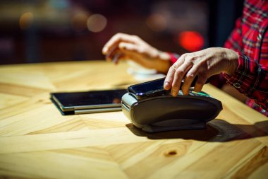 Temassız ödeme. Ödeme telefonla yapılacak. Kafe ya da restoran müşterisi ödemeyi cep telefonuyla yaparken elektronik ödeme makinesinin üzerinde akıllı telefon tutuyor. Nakit ödeme yok. NFC teknolojisi.