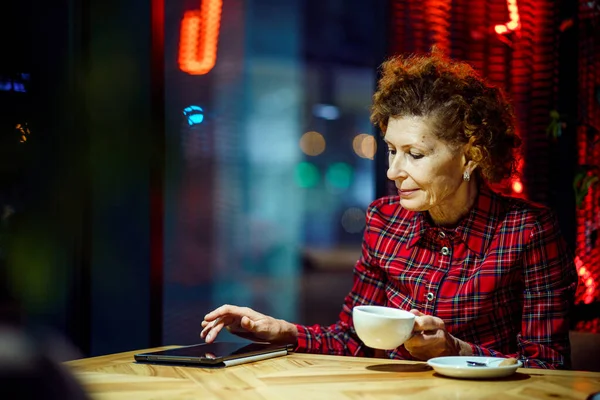 老年妇女在咖啡店里用平板电脑 一个成熟的女人在一家有平板电脑的餐厅里放松 老年女性在咖啡店使用数码平板电脑 老年和人的概念 成熟学生 — 图库照片