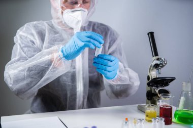 Bilim adamlarının elinde beyaz toz, yasadışı eczane üretimi ve uyuşturucu bulunan ampuller var. Laboratuvar asistanı iğne için cam ampulü inceliyor. Penisilin kuru toz ilacı. Antibiyotik enjeksiyonu.