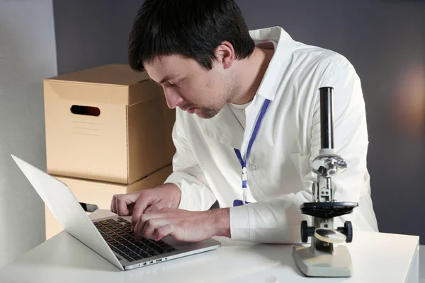 Scientist at workspace in laboratory with microscope, computer, and laboratory tools. Bio technology. Med students stuff. Medical assistant. Scientific research. Checking results on laptop in lab.