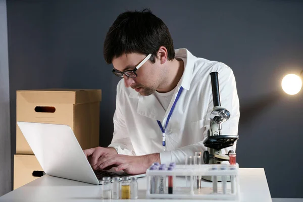 Scientist at workspace in laboratory with microscope, computer, and laboratory tools. Bio technology. Med students stuff. Medical assistant. Scientific research. Checking results on laptop in lab.