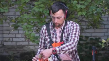 Bahçede çim biçen bir bahçıvan. Benzin fırçası makasıyla çim biçen adam. Benzin budama makinesiyle çim biçme işlemi. Çim biçme işi. Kesici, bahçecilik konsepti. Çim biçme makinesi, millet.