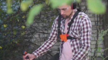 Bahçede çim biçen bir bahçıvan. Benzin fırçası makasıyla çim biçen adam. Benzin budama makinesiyle çim biçme işlemi. Çim biçme işi. Kesici, bahçecilik konsepti. Çim biçme makinesi, millet.