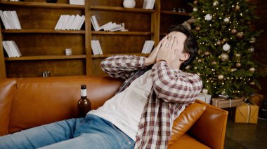 Alcohol addiction at young age. Caucasian male cannot stop drinking alcohol, drunken lonely male drinks wine from bottle. Loneliness, depression and alcoholism during Christmas and New Year holidays. clipart
