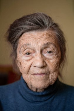 Yaşlı, beyaz, yaşlı, yaşlı, yaşlı, 90 yaşında bir büyükanne dikkatli görünüyor ve gülümsüyor, mutlu hissediyor, büyük bir portre, yüzü kırışık ve gri saçlı. Tema emeklileri, yaşlılar ve uzun ömürlü kadınlar.