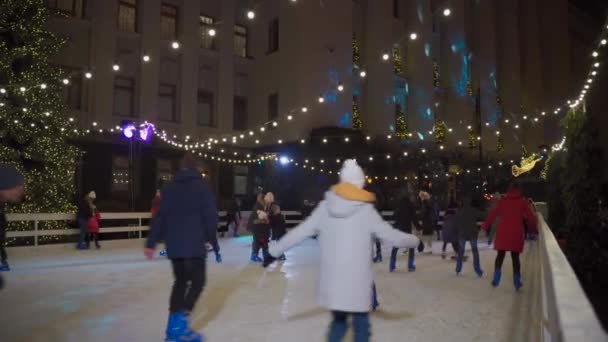 Verbringen Sie die Neujahrs- und Weihnachtsfeiertage aktiv mit den Familien, beim Schlittschuhlaufen in der Eisbahn am Abend. Weihnachtsmarkt und Eisbahn in Kiew, Ukraine in der St. Bank Str in der Nähe des Präsidentenbüros 23. Dezember 2020 — Stockvideo