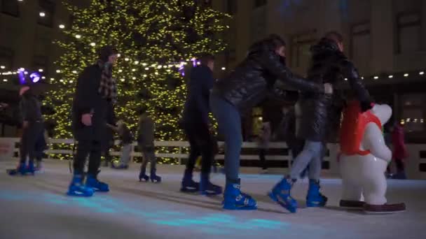 Glückliche Menschen beim Schlittschuhlaufen auf der Eisbahn. Winterszene. Aktive Erholung im Winter in der Eisarena. Weihnachtsmarkt und Eisbahn in Kiew, Ukraine St. Bankova Street in der Nähe des Präsidentenbüros 23. Dezember 2020 — Stockvideo