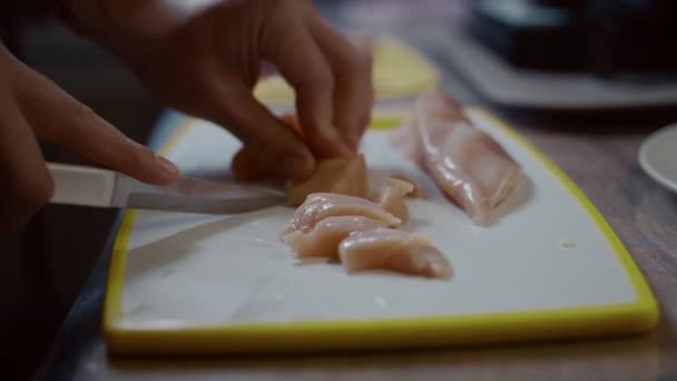 Close-up handen van blanke jonge man snijden vers kippenvlees op plastic wit bord thuis in de keuken. Hobby koken, vrijgezel koken. Een eenzame man bereidt gevogelte voor de lunch — Stockvideo