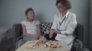 Kıdemli kadın antrenman yetenekleri tahta bloklar inşa eder, kule inşa eder ve düşmesine izin vermemeye çalışır, oyun. Eski hasta bloğu kaldırır, üstüne yerleştirir, terapi sırasında bunamayı destekler.