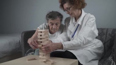 Kıdemli kadın antrenman yetenekleri tahta bloklar inşa eder, kule inşa eder ve düşmesine izin vermemeye çalışır, oyun. Eski hasta bloğu kaldırır, üstüne yerleştirir, terapi sırasında bunamayı destekler.
