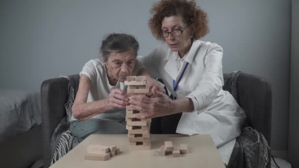 Sessione di conduzione di medici maturi, terapia per pazienti anziani in casa di cura, formazione di abilità motorie fini per la demenza, malattia di Alzheimer e istituto di recupero piegando blocchi di legno, giocando a jenga — Video Stock