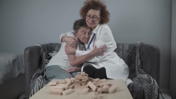 Reifer Arzt leitet Sitzung, Therapie für ältere Patienten im Pflegeheim, Schulung der Feinmotorik bei Demenz, Alzheimer-Krankheit und Heilanstalt durch Klappen von Holzklötzen, Spielen — Stockvideo