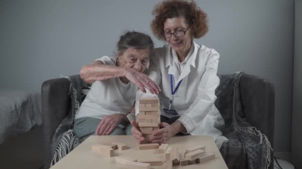 Sessione di conduzione medico maturo, terapia per il paziente anziano in casa di cura, formazione di abilità motorie fini per la demenza, malattia di Alzheimer e istituto di recupero piegando blocchi di legno, giocando — Video Stock