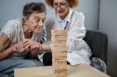 Olgun doktor seansı, huzurevindeki yaşlı hastalar için terapi bunama, alzheimer hastalıkları ve iyileşme enstitüsü için ahşap bloklar katlayarak iyi motor becerileri eğitimi, Jenga oynayarak.