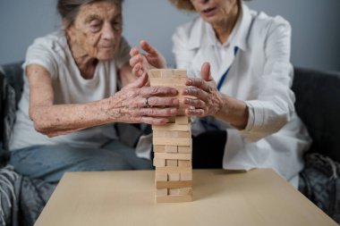 Kıdemli kadın antrenman yetenekleri, tahta bloklar inşa etmek, kule inşa etmek ve yıkılmasına izin vermemeye çalışmak, Jenga oyunu. Eski hasta tıkanıklığı kaldırır, en üstte yer alır, terapi sırasında doktorlara destek olur..
