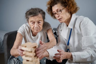 Olgun doktor seansı, huzurevindeki yaşlı hastalar için terapi bunama, alzheimer hastalıkları ve iyileşme enstitüsü için ahşap bloklar katlayarak iyi motor becerileri eğitimi, Jenga oynayarak.