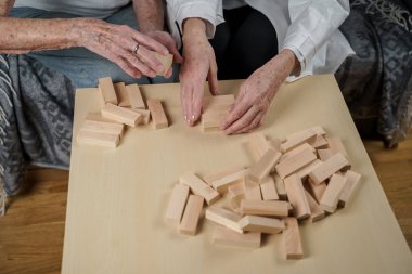 Jenga oynayan yaşlı kadın, bloklardan kule inşa ediyor. Beyaz laboratuvar önlüklü yaşlı doktor, kıdemli hastayı destekliyor, mantık geliştiriyor, iyi motor beceriler geliştiriyor, evde yaşlı yalnız kadın hastalıkları var..