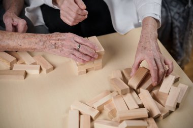 Jenga oynayan yaşlı kadın, bloklardan kule inşa ediyor. Beyaz laboratuvar önlüklü yaşlı doktor, kıdemli hastayı destekliyor, mantık geliştiriyor, iyi motor beceriler geliştiriyor, evde yaşlı yalnız kadın hastalıkları var..
