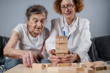 Olgun doktor seansı, huzurevindeki yaşlı hastalar için terapi bunama, alzheimer hastalıkları ve iyileşme enstitüsü için ahşap bloklar katlayarak iyi motor becerileri eğitimi, Jenga oynayarak.