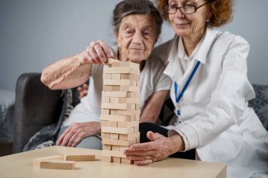 Kıdemli kadın antrenman yetenekleri, tahta bloklar inşa etmek, kule inşa etmek ve yıkılmasına izin vermemeye çalışmak, Jenga oyunu. Eski hasta tıkanıklığı kaldırır, en üstte yer alır, terapi sırasında doktorlara destek olur..