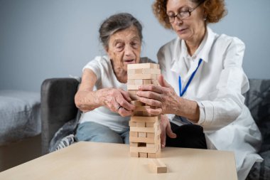 Olgun doktor seansı, huzurevindeki yaşlı hastalar için terapi bunama, alzheimer hastalıkları ve iyileşme enstitüsü için ahşap bloklar katlayarak iyi motor becerileri eğitimi, Jenga oynayarak.
