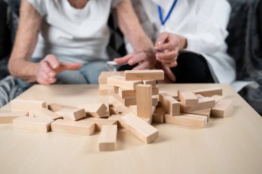 Bunama terapisi, parmaklar ve motor beceriler geliştirmek, kuleye tahta bloklar yapmak, Jenga oynamak. Yaşlı kadın 90 yaşında ve doktor huzurevinde eğitim oyunu oynuyor.