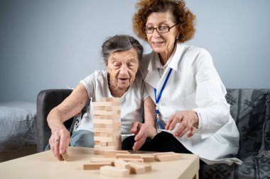 Kıdemli kadın antrenman yetenekleri, tahta bloklar inşa etmek, kule inşa etmek ve yıkılmasına izin vermemeye çalışmak, Jenga oyunu. Eski hasta tıkanıklığı kaldırır, en üstte yer alır, terapi sırasında doktorlara destek olur..