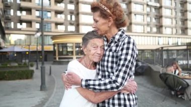 Neşeli bir an. Aile bağlantısı. Yaşlı bakımı. Kızı büyük anneye sarılıyor. Sarılma konsepti. Gülümseyen kadın ve yaşlı anne kucaklaşıp birlikte eğleniyorlar. Mutlu kadın iki kuşak aile aşkı