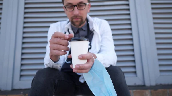 Zbliżenie Dłoni Filiżanką Kawy Ochronną Maską Medyczną Zmęczony Wyczerpany Lekarz — Zdjęcie stockowe