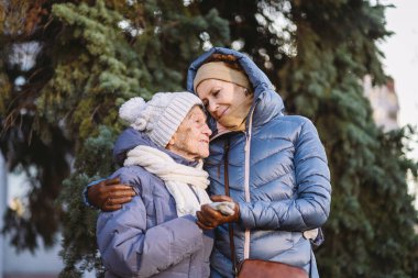 Annelik. Temanın önemi, bayramlarda yaşlı bekar ebeveynleri ziyaret etmek ve onlarla vakit geçirmek. Büyük anne ve yetişkin kız mutlu aile kucaklaşması ve gülüşmeler Park arka planında kışın Noel ağacı.