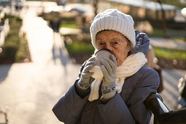 快乐的老太太拿着咖啡去了 在城里穿衣过冬 漂亮的老太太要去喝杯咖啡 老年时积极休息 散步时喝咖啡休息 热饮料 退休90年 — 图库照片