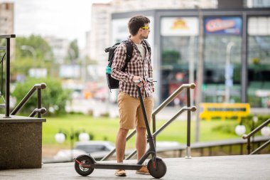 Gezgin genç ve çekici turist trafik sıkışıklığı olmadan şehirde dolaşmak için eko elektrikli scooter kullanıyor. Tema, şehirde alternatif çevre dostu ulaşım, kişisel hareketlilik..