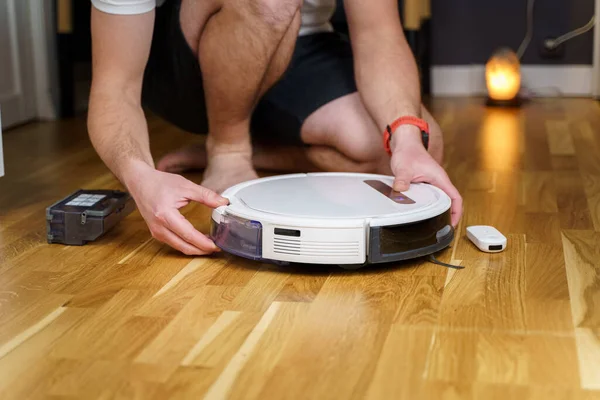 Robot vacuum cleaner repair. Man fixing robot vacuum cleaner DIY at home on the floor. Robotic vacuum cleaner maintenance and service. Smart device for easy housework. New tech for households.