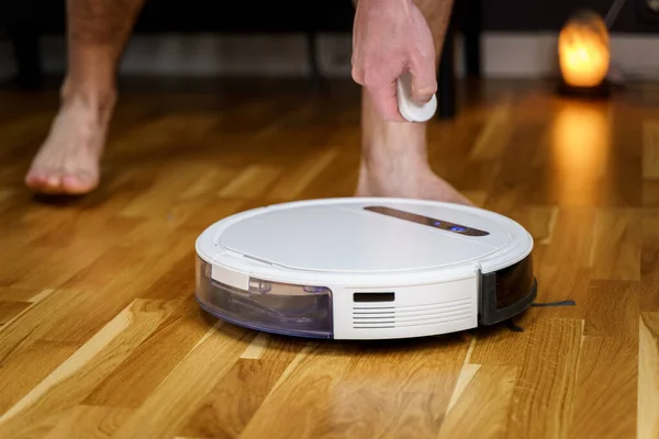 Robot vacuum cleaner repair. Man fixing robot vacuum cleaner DIY at home on the floor. Robotic vacuum cleaner maintenance and service. Smart device for easy housework. New tech for households.