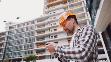 İnşaat alanında akıllı telefonla çalışan bir mimar. Mühendis, akıllı telefondan inşaat planını kontrol et. İnşaat müfettişi, akıllı telefon ekranındaki tesislerdeki inşaat projesini doğruladı.