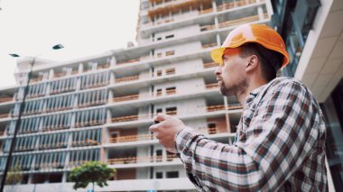 İnşaat alanında akıllı telefonla çalışan bir mimar. Mühendis, akıllı telefondan inşaat planını kontrol et. İnşaat müfettişi, akıllı telefon ekranındaki tesislerdeki inşaat projesini doğruladı.