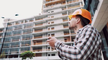 İnşaat alanında akıllı telefonla çalışan bir mimar. Mühendis, akıllı telefondan inşaat planını kontrol et. İnşaat müfettişi, akıllı telefon ekranındaki tesislerdeki inşaat projesini doğruladı.